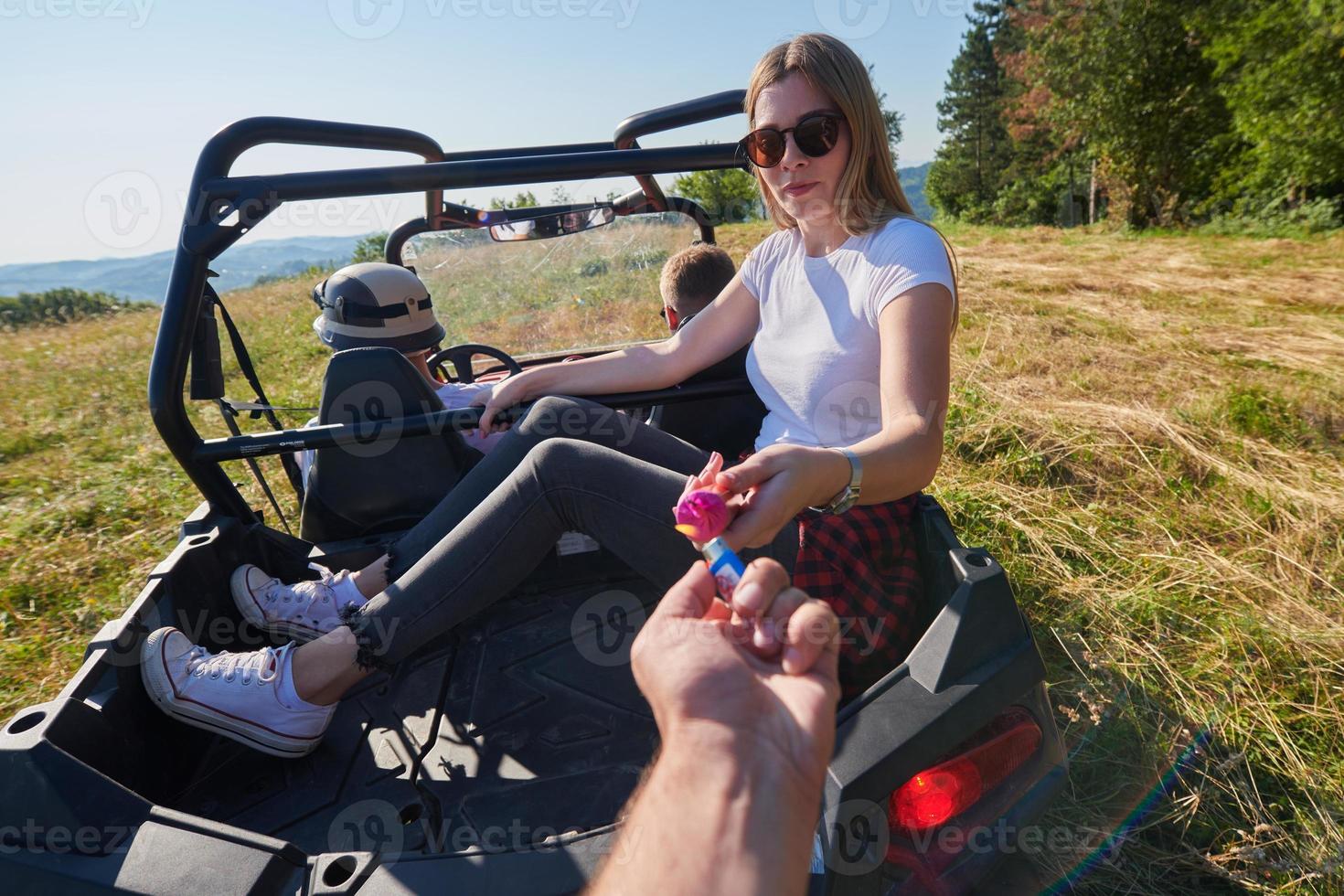 excited people having fun enjoying beautiful sunny day holding colorful torches while driving a off road buggy car photo