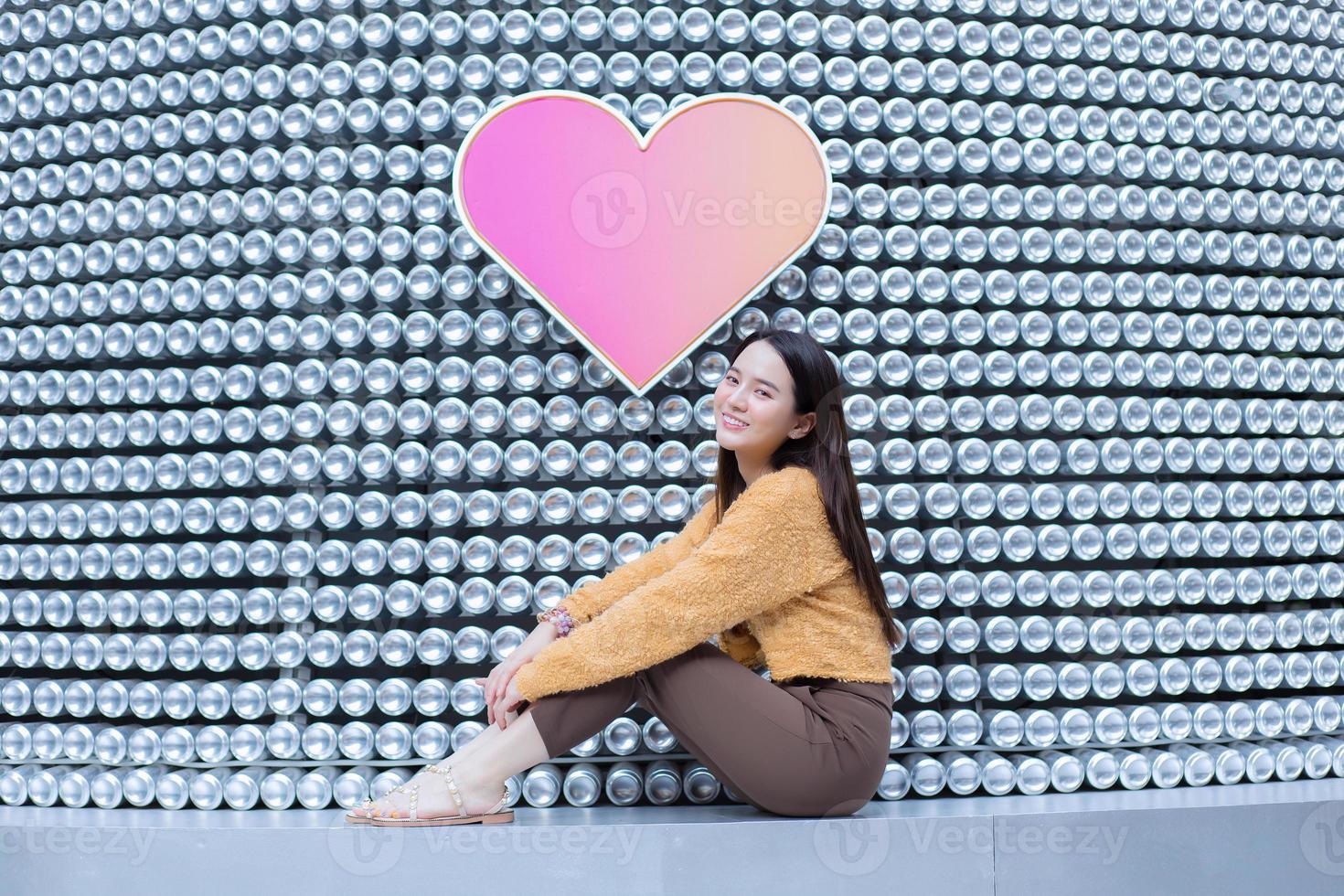 Asian pretty woman in long hair wears a yellow sweater and brightly smiles in Valentine s theme. photo