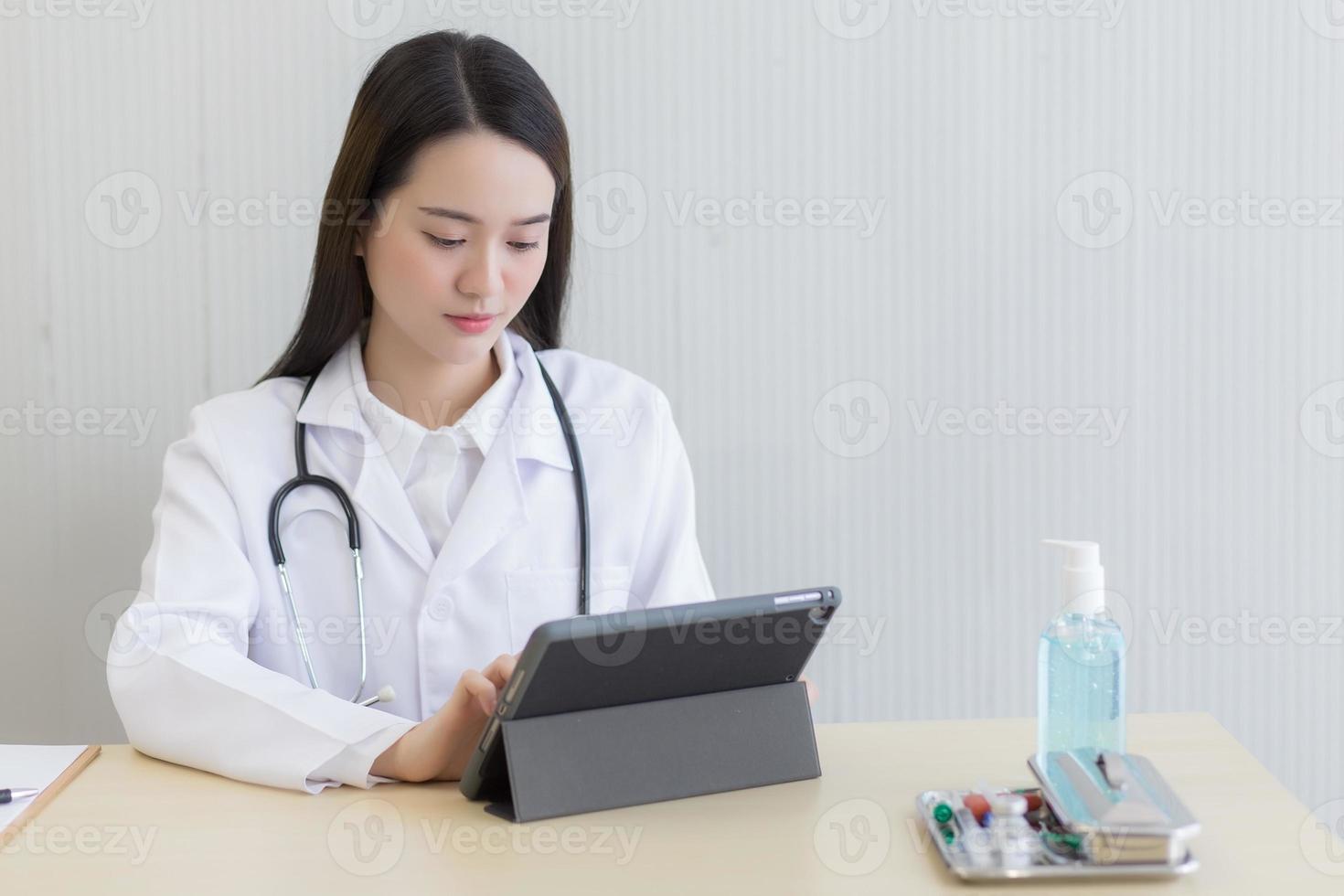 Coronavirus protection concept. Serious professional doctor wearing white coat and stethoscope holding modern touchscreen gadget using digital tablet computer at work. photo