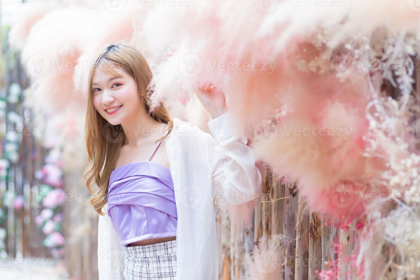 Asian beautiful woman with long bronze hair who wears short skirt and white long sleeve stands in the colorful garden. photo