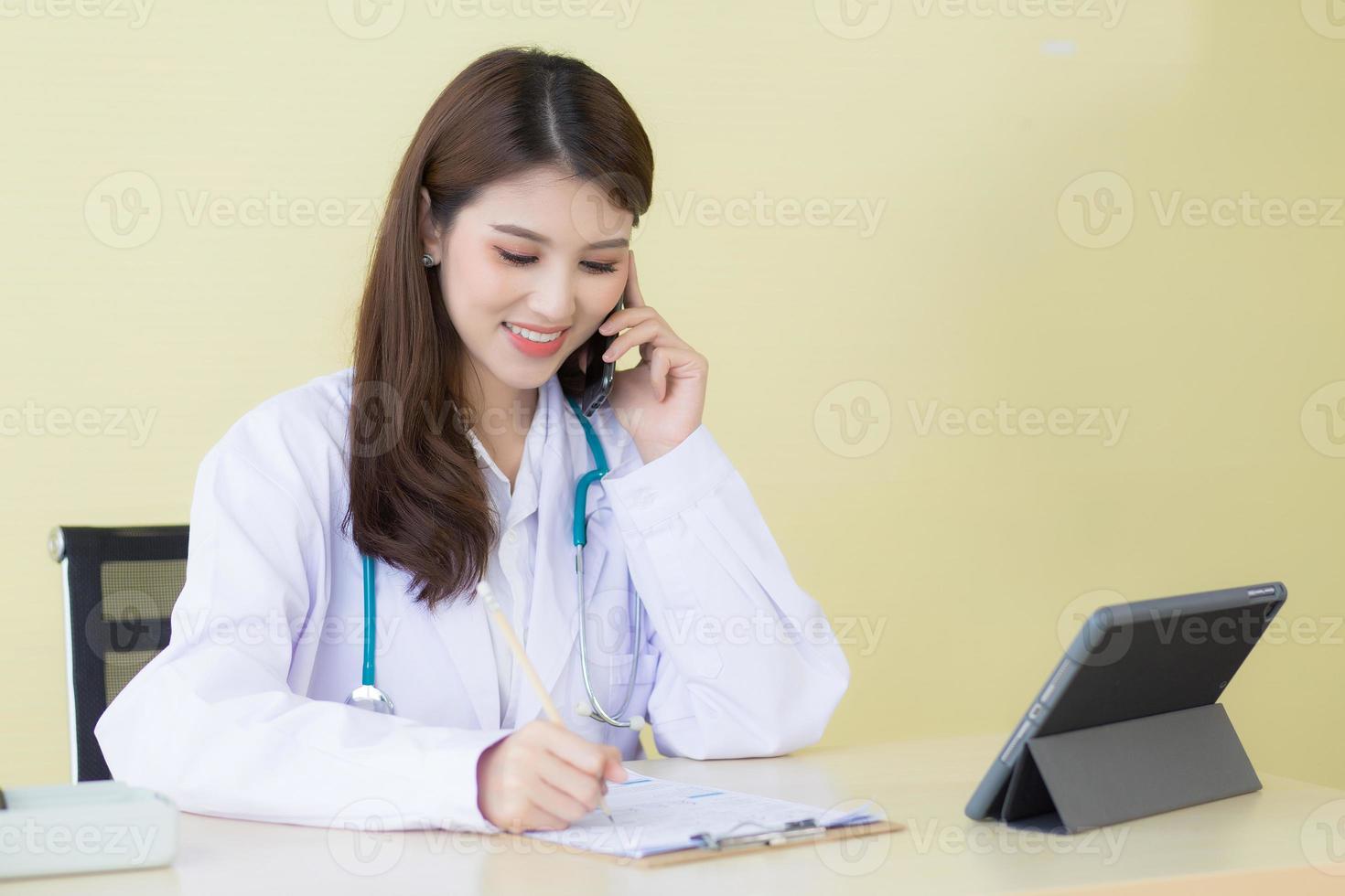 una hermosa doctora llama al teléfono y escribe para verificar el síntoma foto