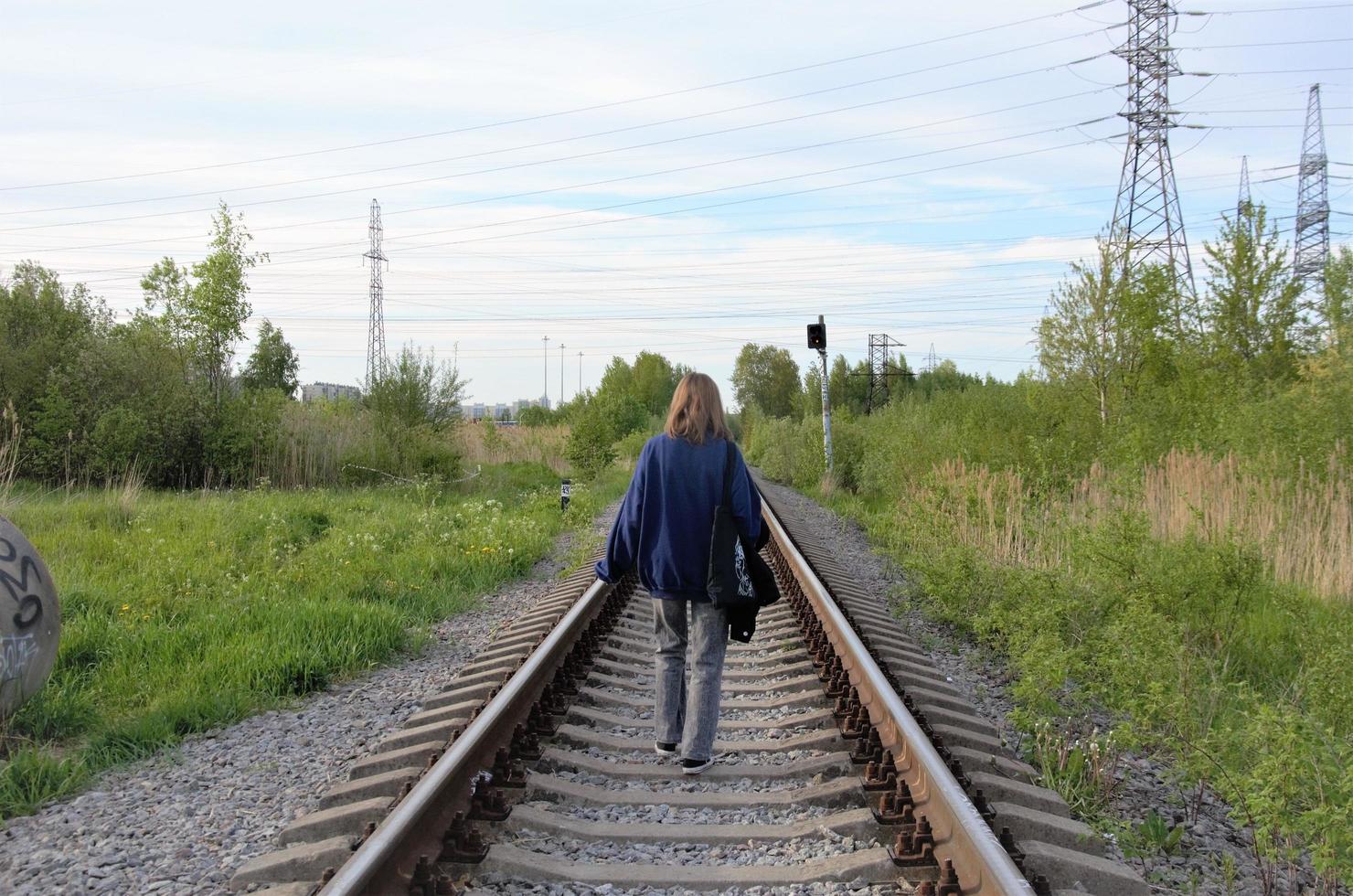 a teenager walks on the rails in front of photo