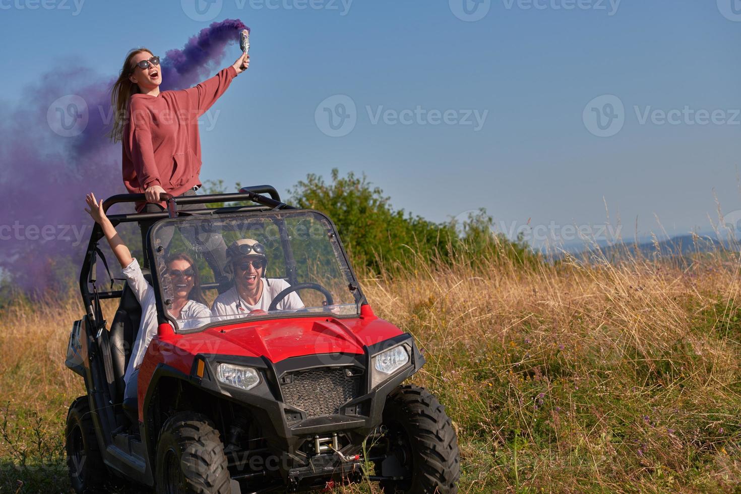 excited people having fun enjoying beautiful sunny day holding colorful torches while driving a off road buggy car photo