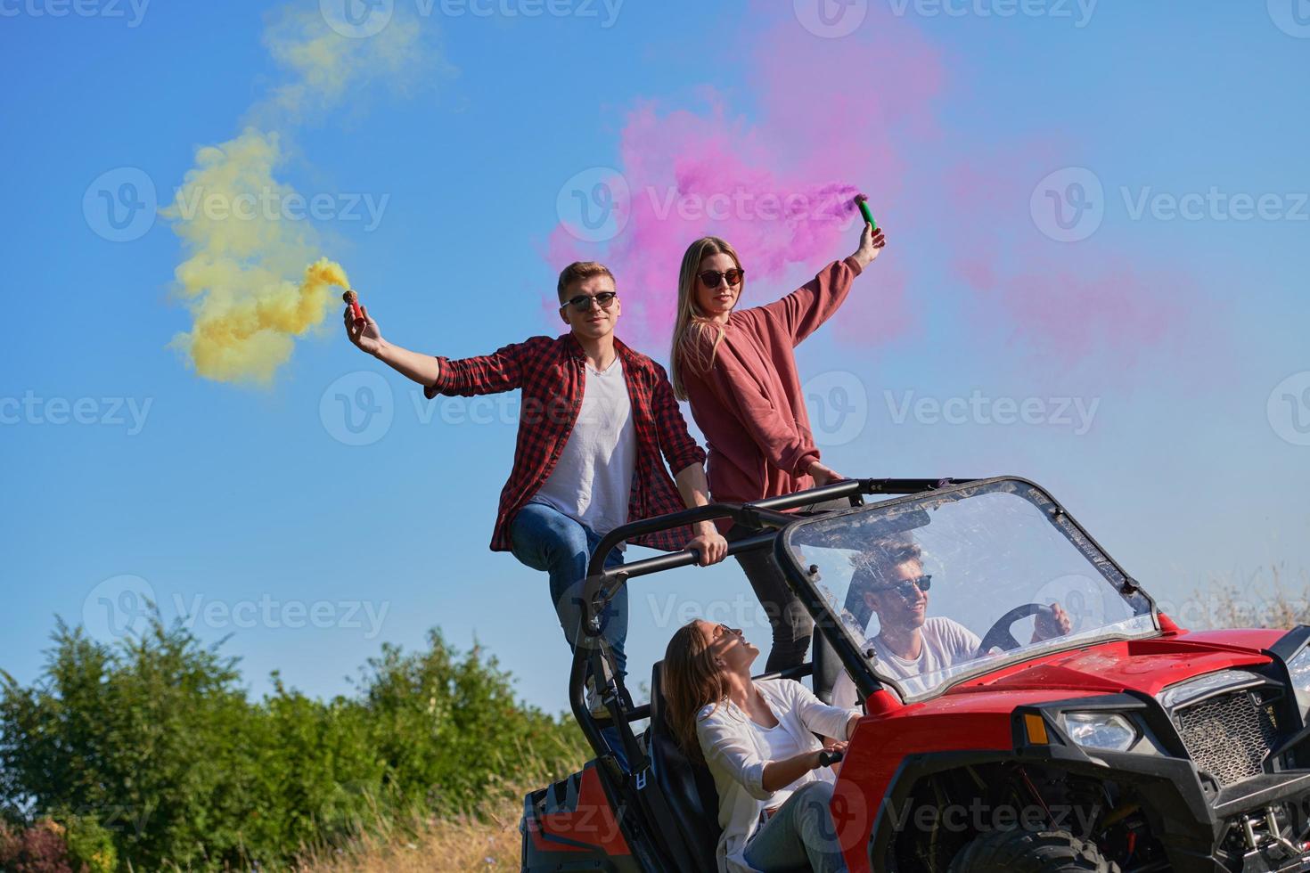 excited people having fun enjoying beautiful sunny day holding colorful torches while driving a off road buggy car photo