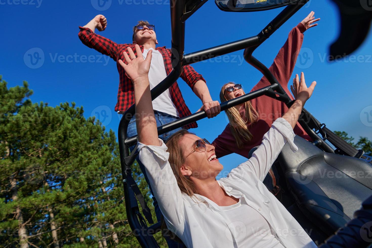 group young happy people enjoying beautiful sunny day while driving a off road buggy car photo