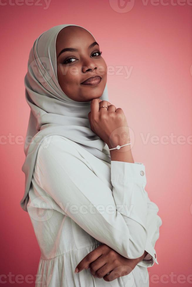 retrato de una joven belleza afro musulmana moderna con ropa islámica tradicional sobre fondo rosa plástico. enfoque selectivo foto