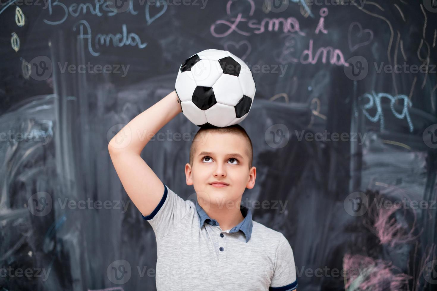 happy boy holding a soccer ball on his head photo