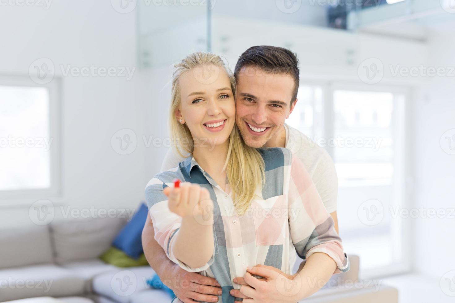 pareja mostrando una pequeña casa roja en las manos foto