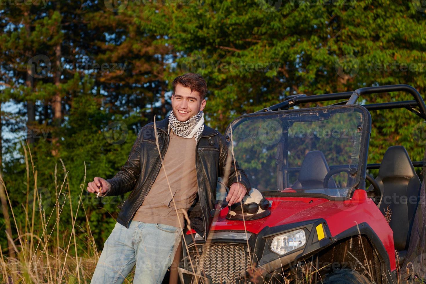 man enjoying beautiful sunny day smoking a cigarette while taking a break from driving a off road buggy car photo