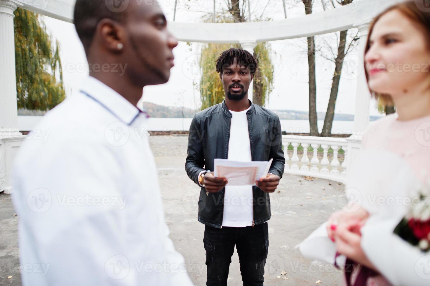 Wedding engagement ceremony with pastor. Happy multiethnic couple in love story. Relationships of african man and white european woman. photo