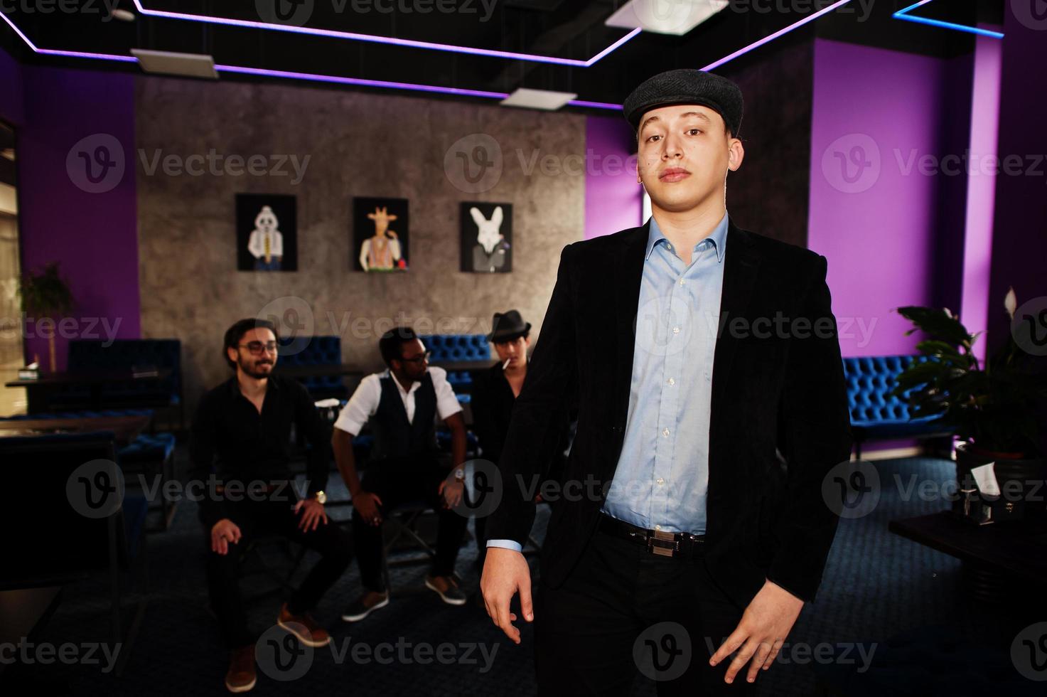 Stylish arab man against group of handsome retro well-dressed guys gangsters spend time at club. Multiethnic male bachelor mafia party in restaurant. photo
