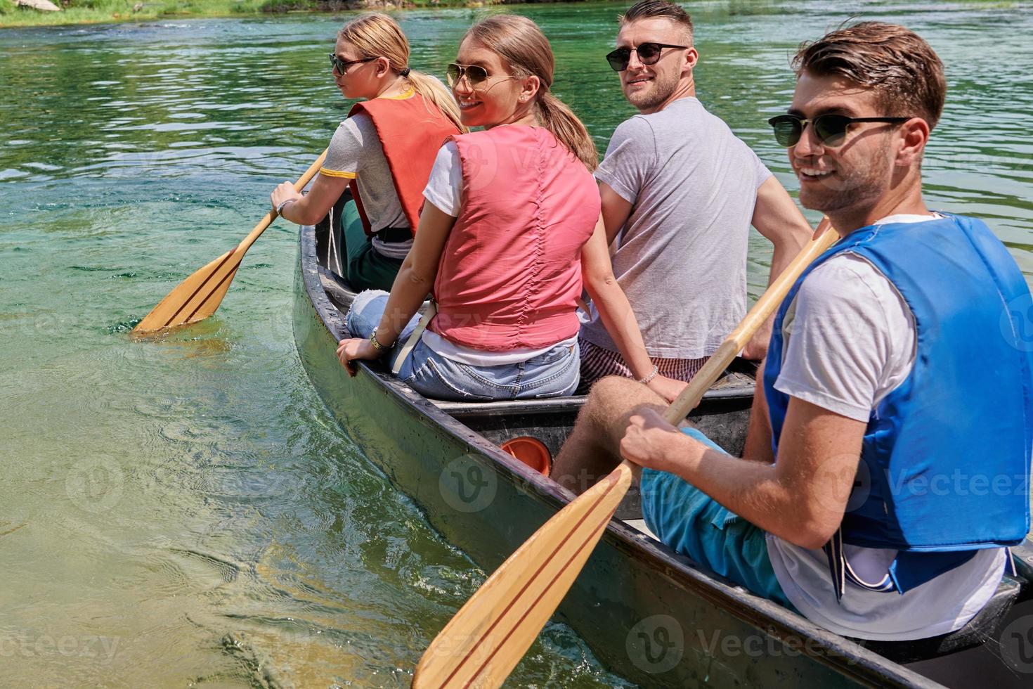 Group adventurous explorer friends are canoeing in a wild river photo