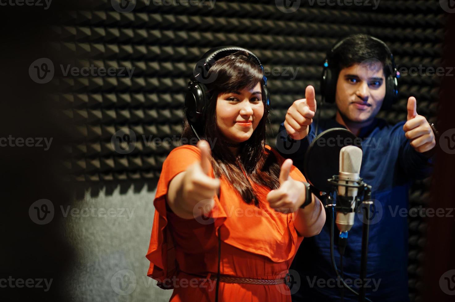 Young asian duet singers with microphone recording song in record music studio. photo