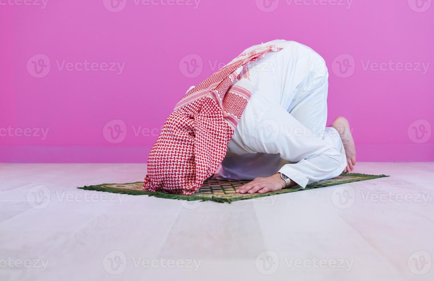 young arabian muslim man praying on the floor at home photo