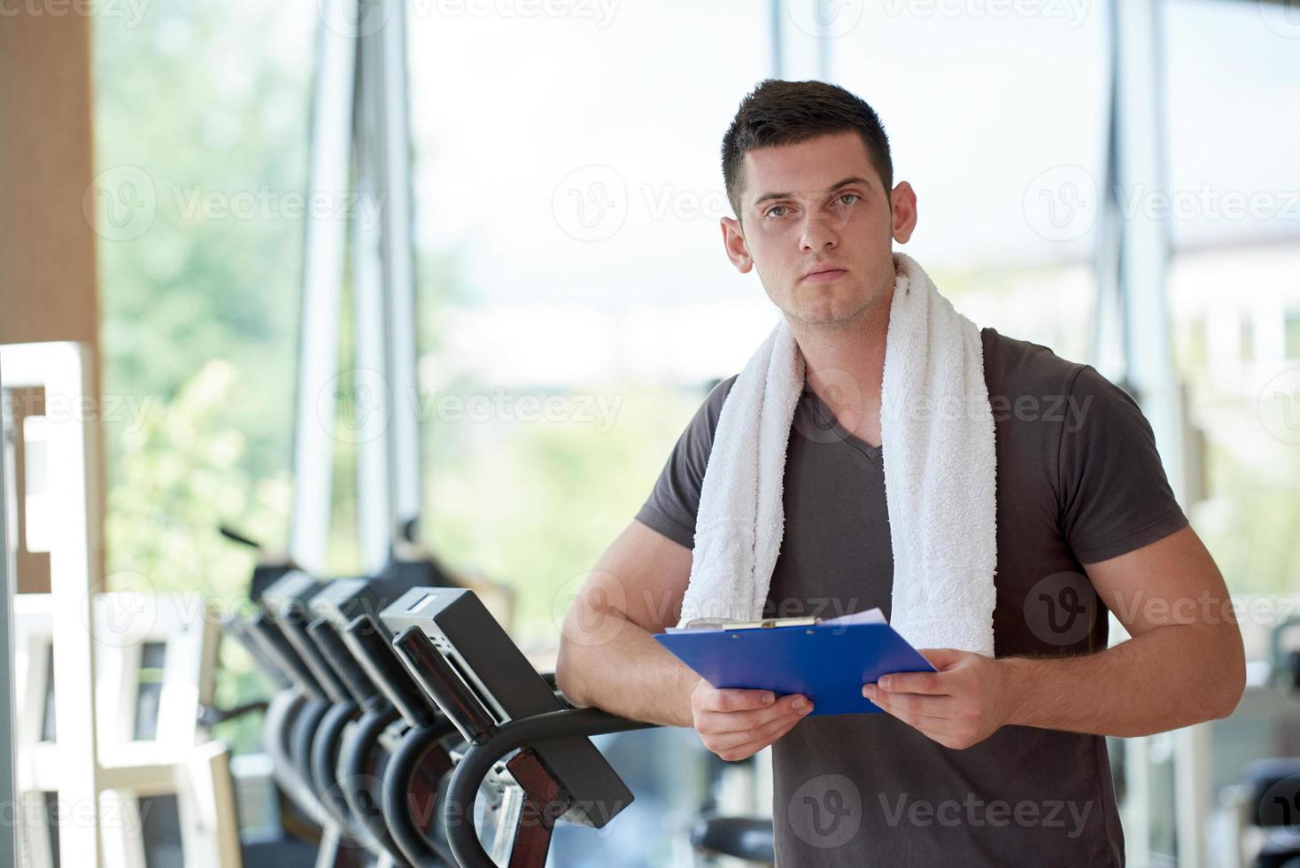 trainer with clipboard standing in a bright gym photo