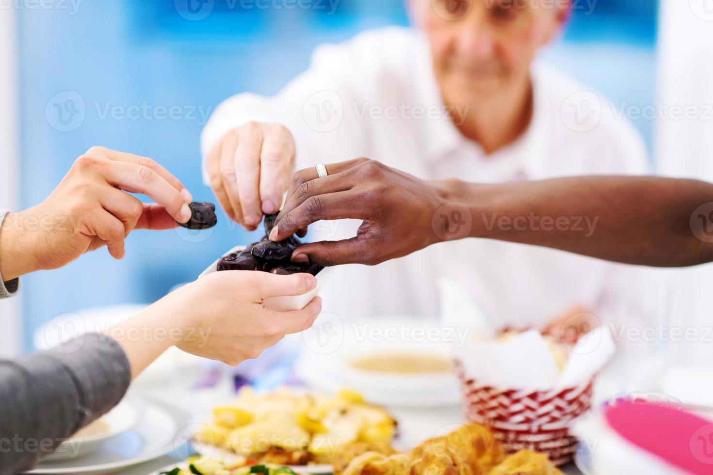 familia musulmana multiétnica moderna compartiendo un cuenco de dátiles foto