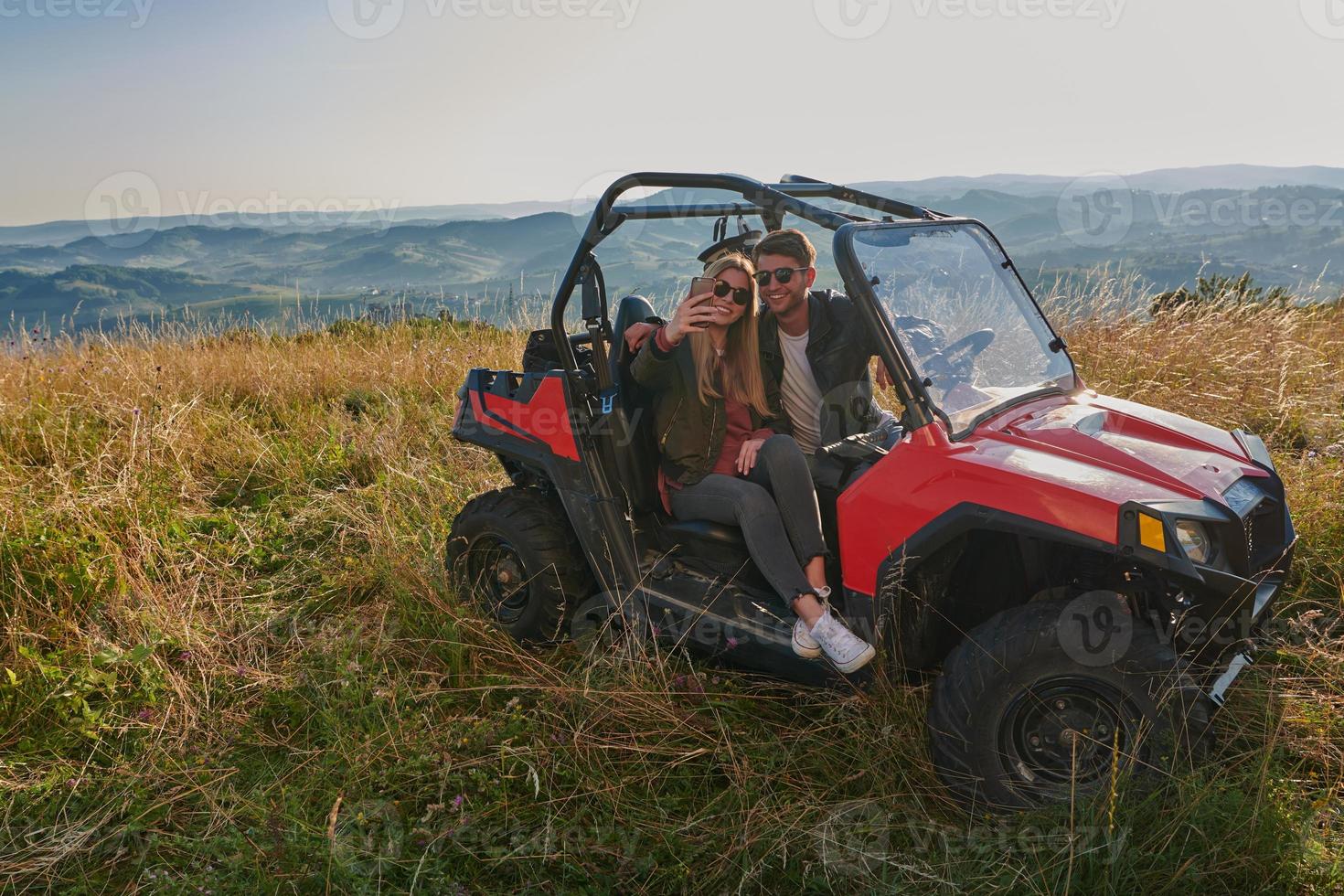 couple enjoying beautiful sunny day taking selfie picture while driving a off road buggy photo