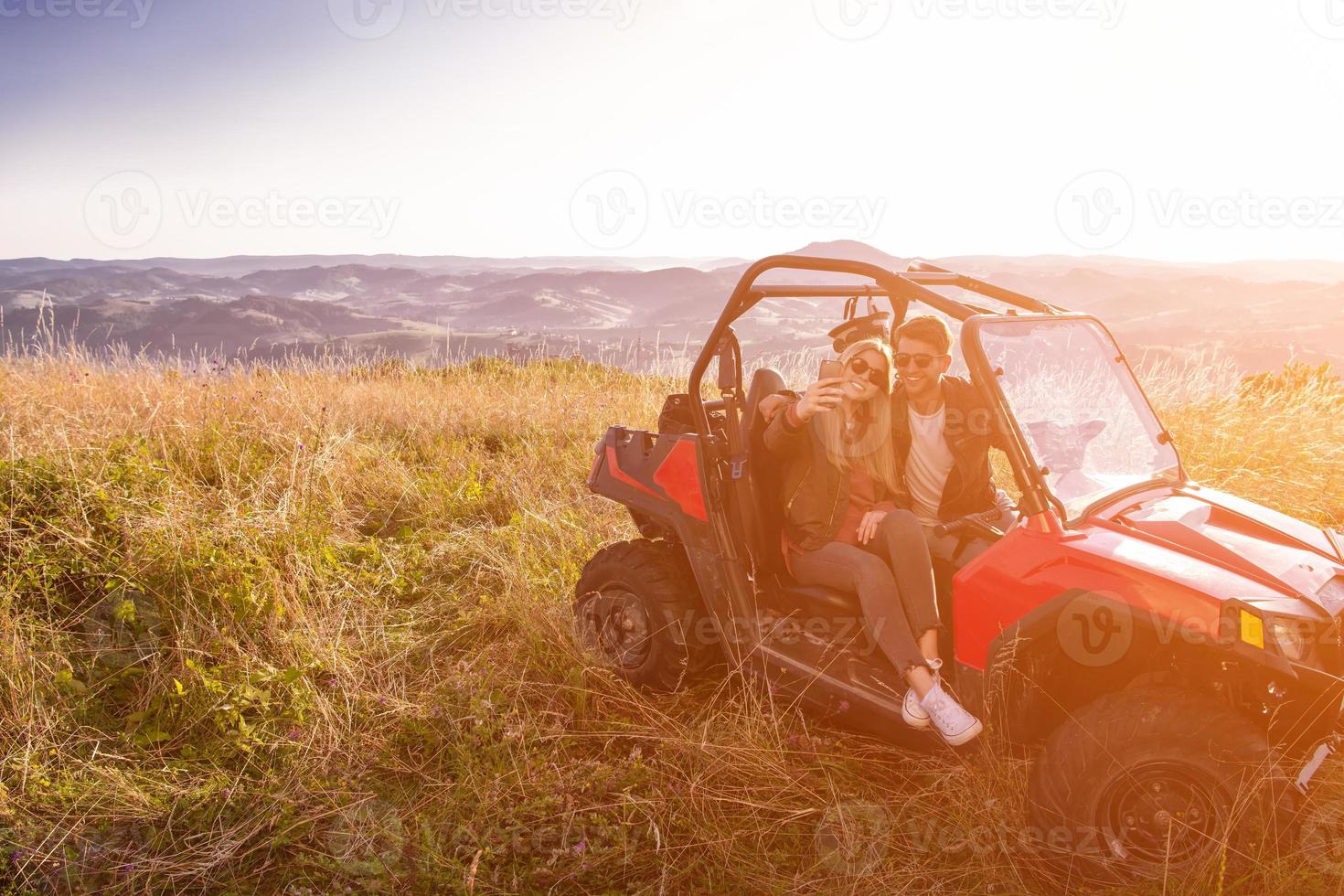 young couple taking selfie picture while driving a off road buggy photo