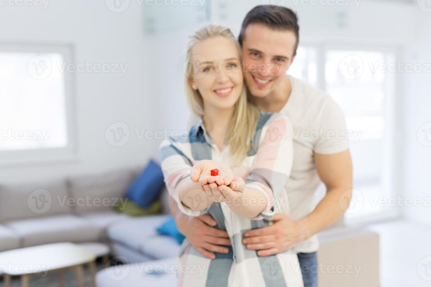 pareja mostrando una pequeña casa roja en las manos foto