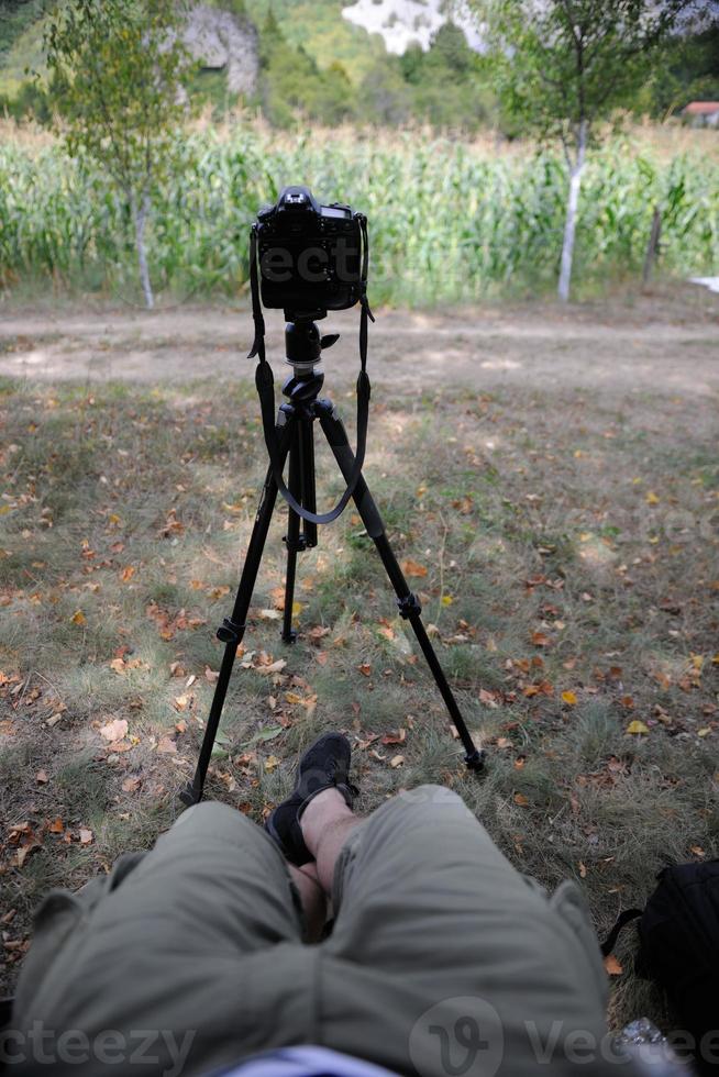 pov photographer in nature taking timelapse photo on pro dslr camera with tripod