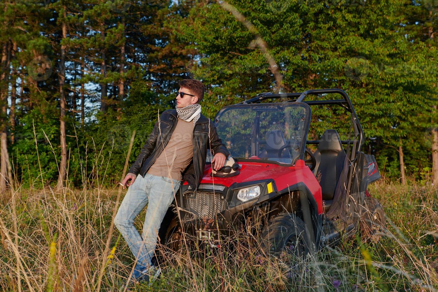 man enjoying beautiful sunny day smoking a cigarette while taking a break from driving a off road buggy car photo