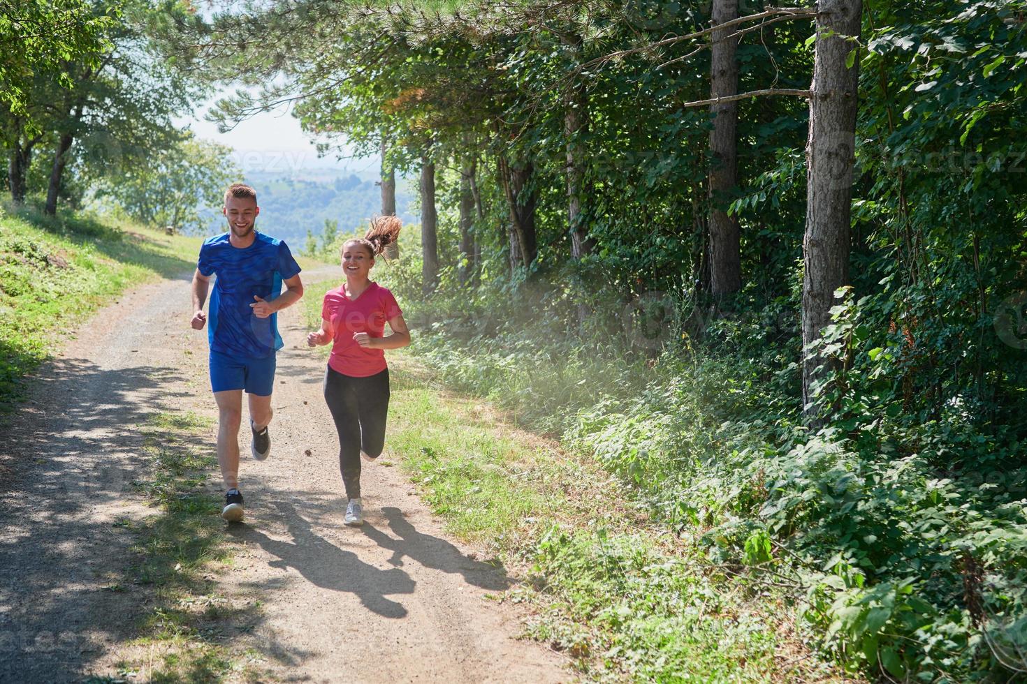 couple enjoying in a healthy lifestyle while jogging on a country road photo