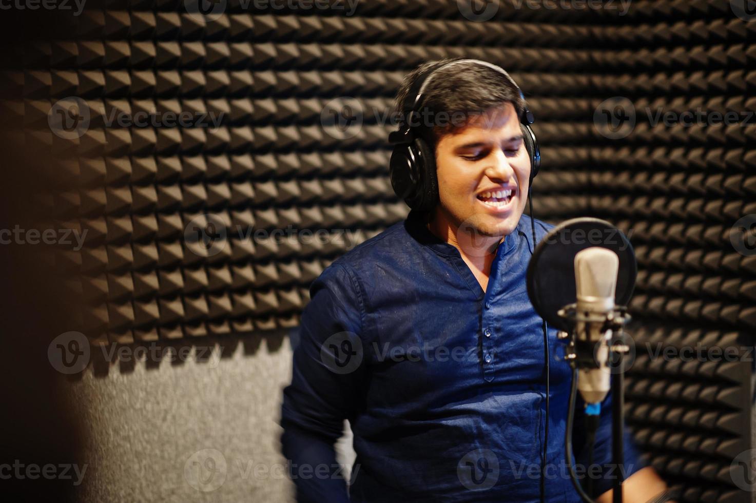 Young asian singer man with microphone recording song in record music studio. photo