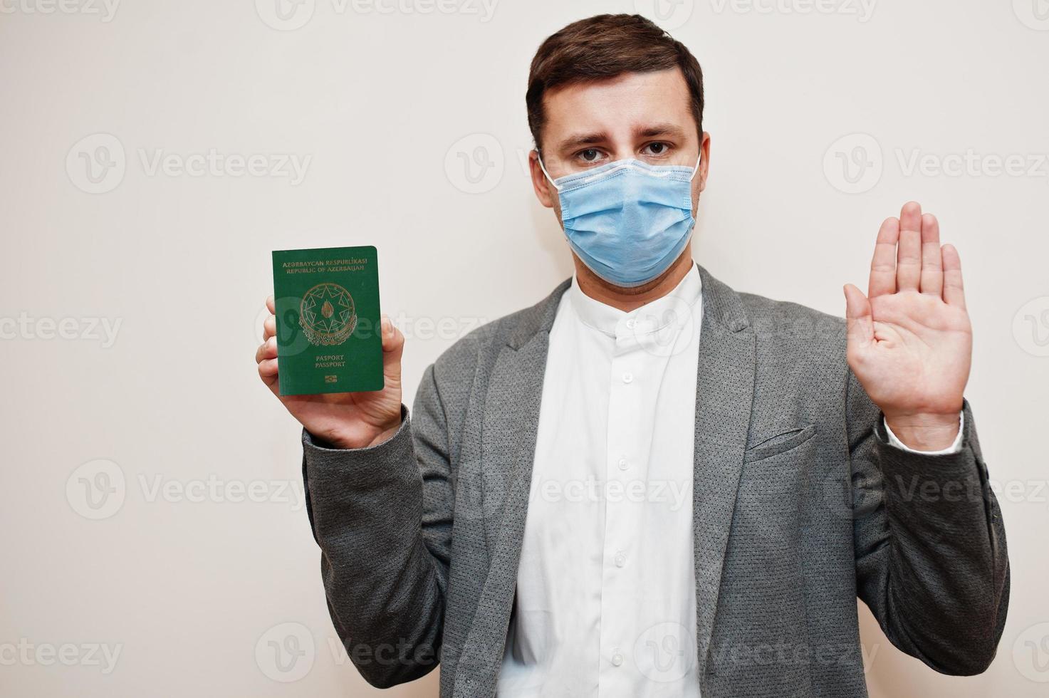 European man in formal wear and face mask, show Azerbaijan passport with stop sign hand. Coronavirus lockdown in Europe country concept. photo