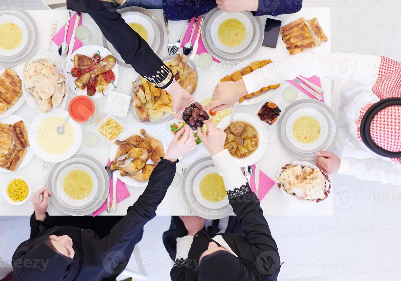 Muslim family having Iftar dinner eating dates to break feast top view