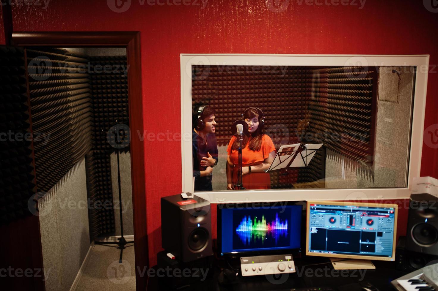 Young asian duet singers with microphone recording song in record music studio. photo