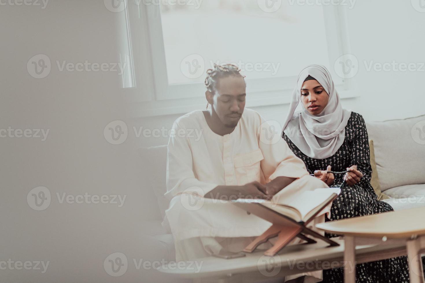 pareja musulmana africana en casa en ramadán leyendo el libro de holly islam del corán. foto