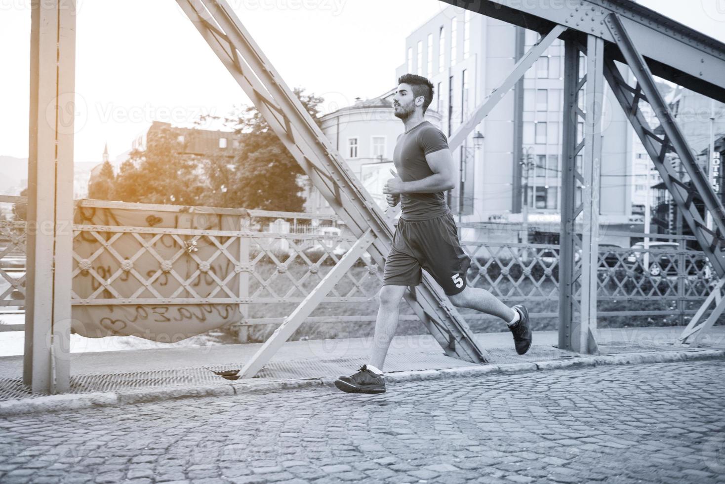 hombre corriendo por el puente en la mañana soleada foto