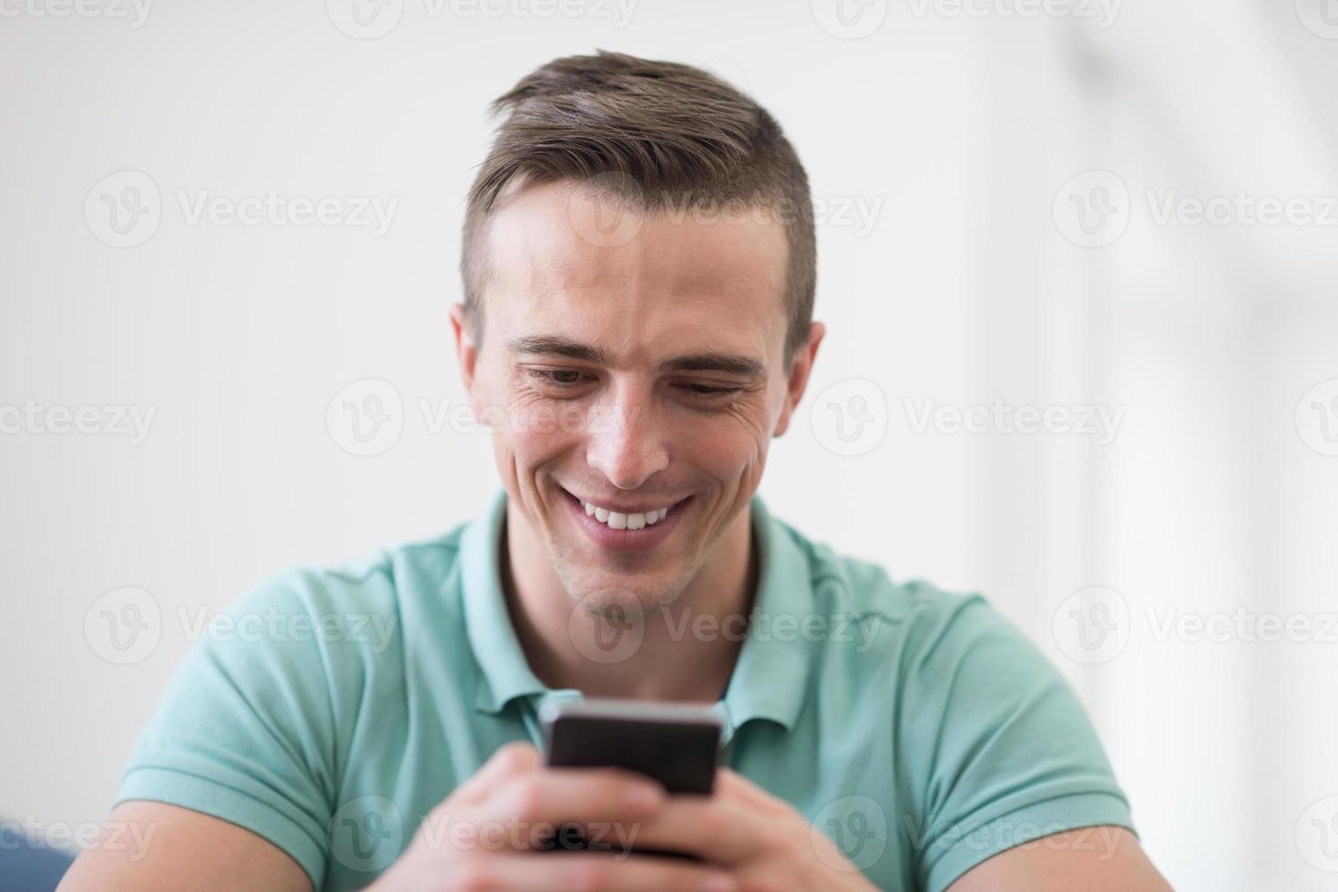 young man using a mobile phone  at home photo