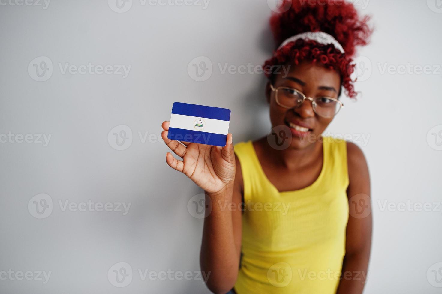 African american woman with afro hair, wear yellow singlet and eyeglasses, hold Nicaragua flag isolated on white background. photo