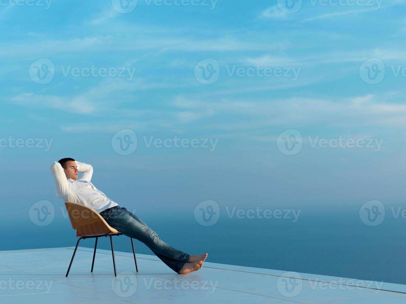 relaxed young man at home on balcony photo