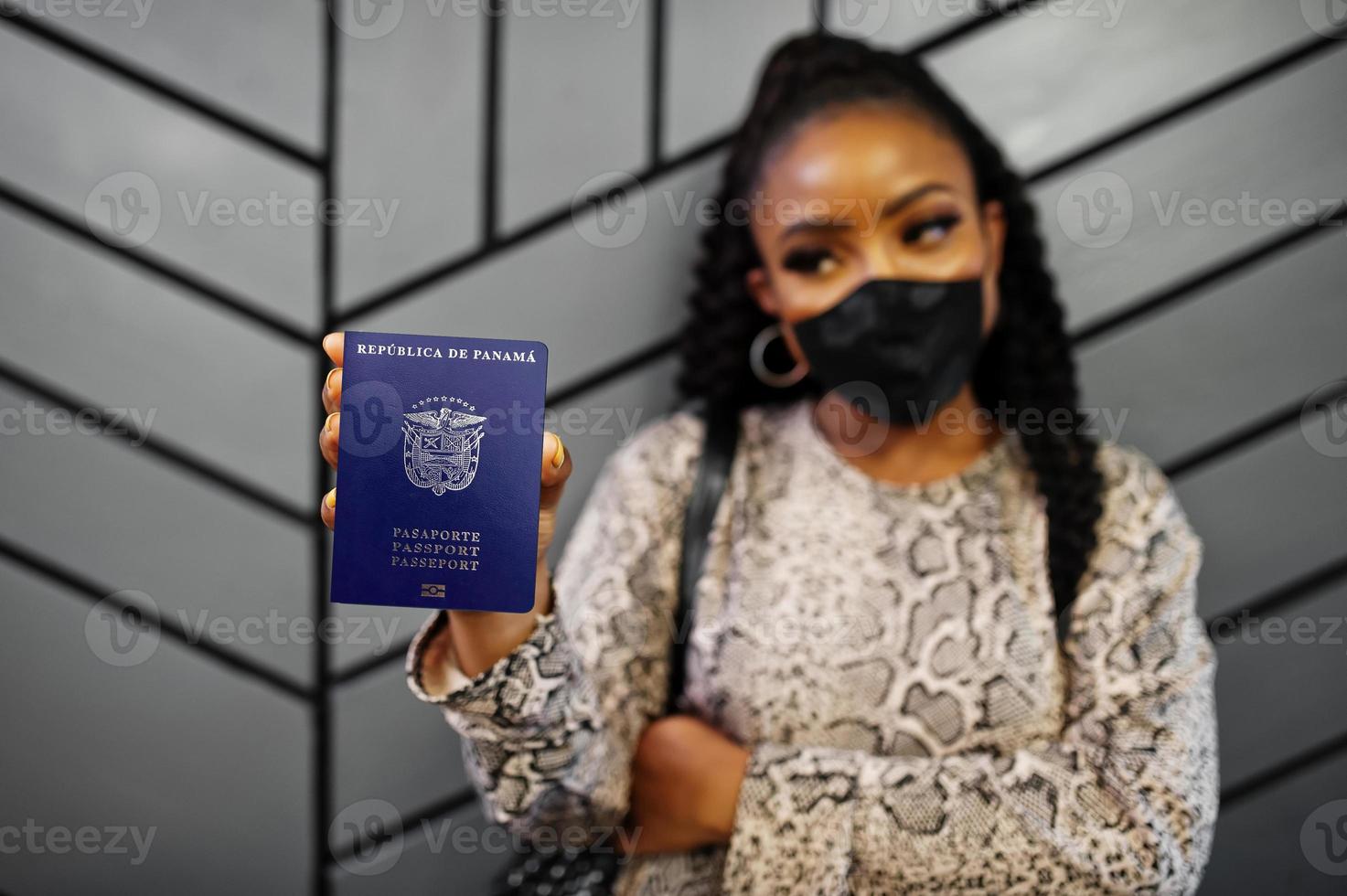 African american woman wearing black face mask show Panama passport in hand. Coronavirus in America country, border closure and quarantine, virus outbreak concept. photo