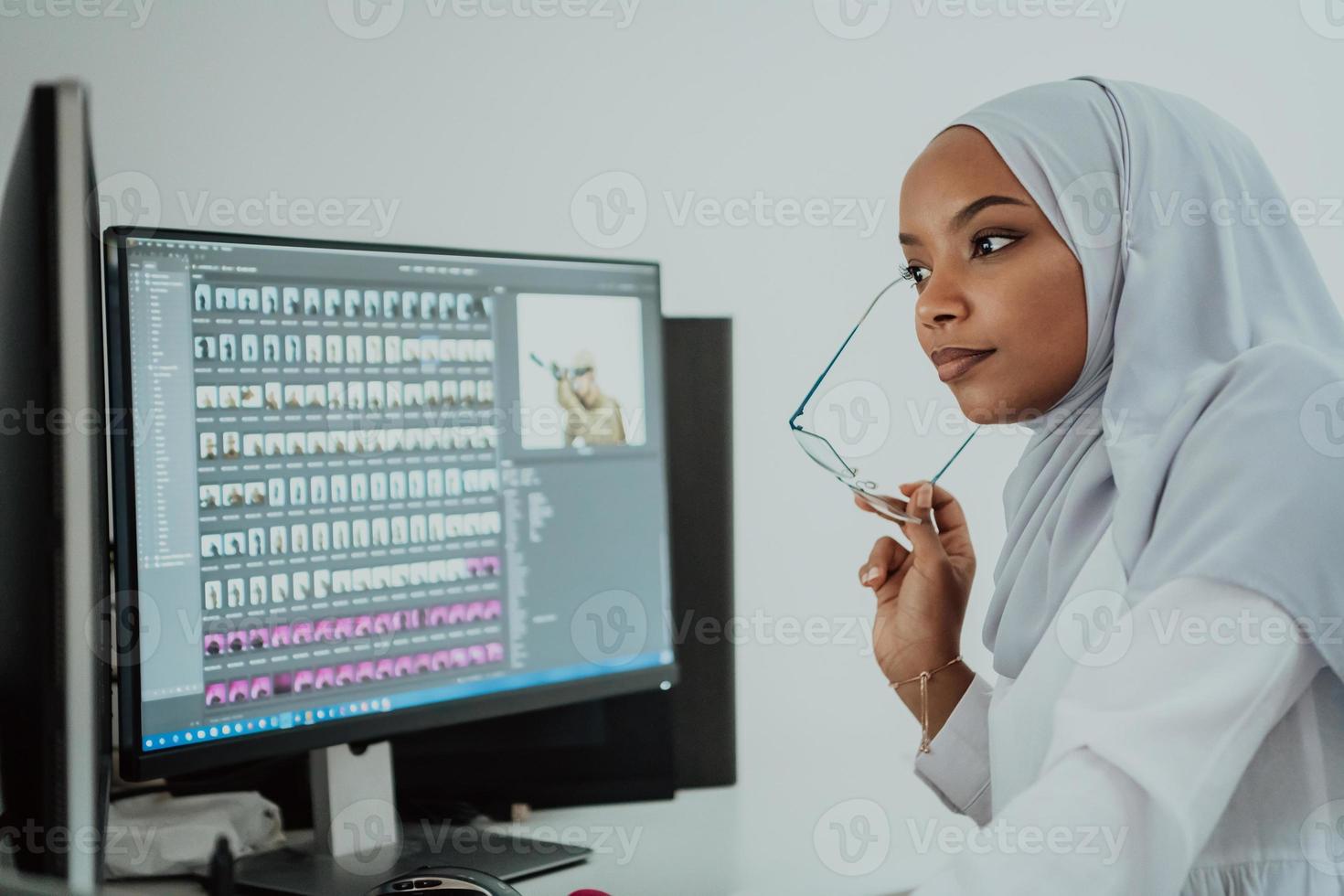 Young Afro-American modern Muslim businesswoman wearing a scarf in a creative bright office workplace with a big screen. photo