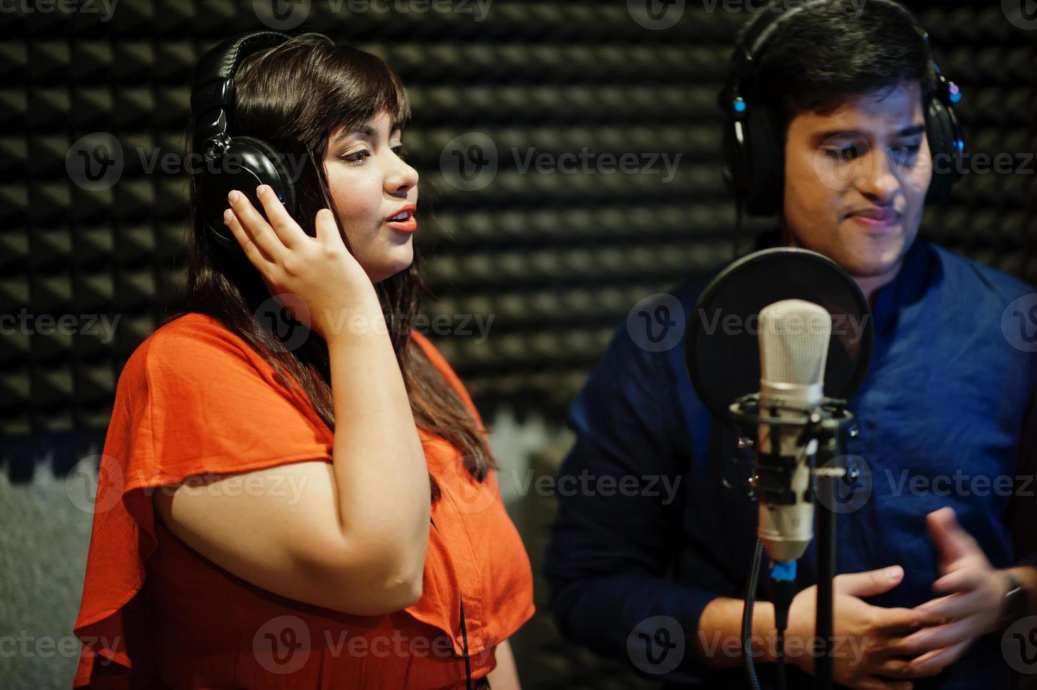 Young asian duet singers with microphone recording song in record music studio. photo