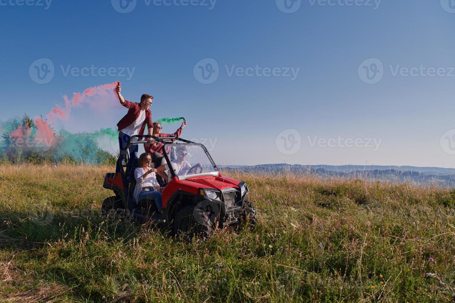 excited people having fun enjoying beautiful sunny day holding colorful torches while driving a off road buggy car photo