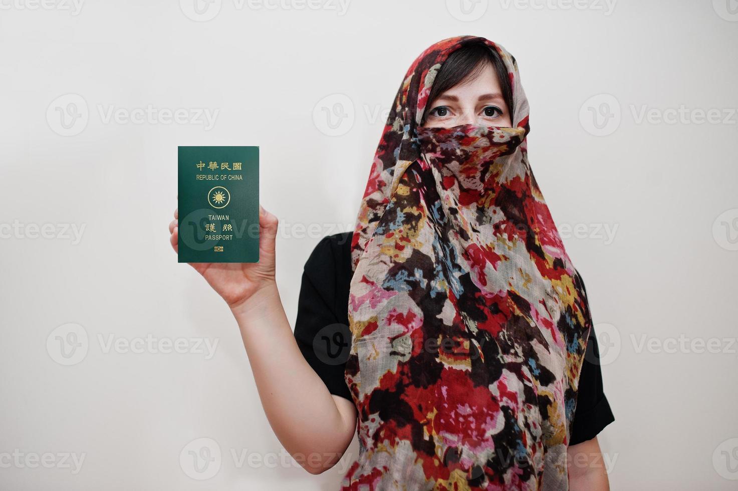 Young arabian muslim woman in hijab clothes hold Republic of China passport on white wall background, studio portrait. photo