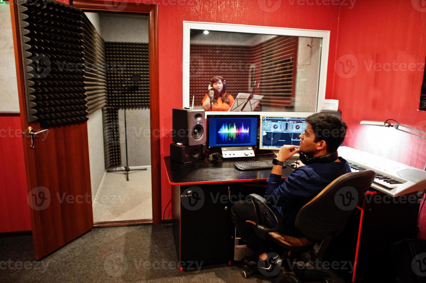 Young asian singer with microphone recording song in record music studio with sound producer. photo