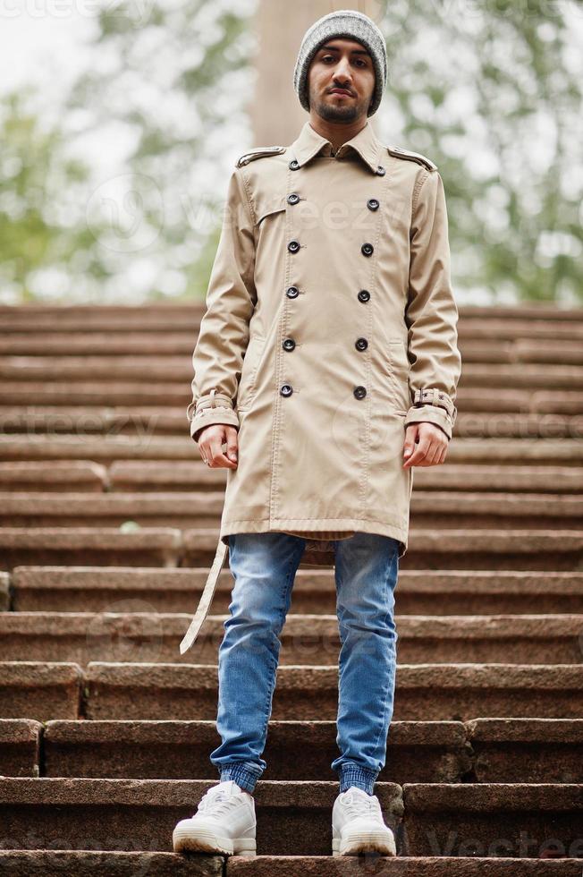 Stylish kuwaiti man at trench coat and hat. photo