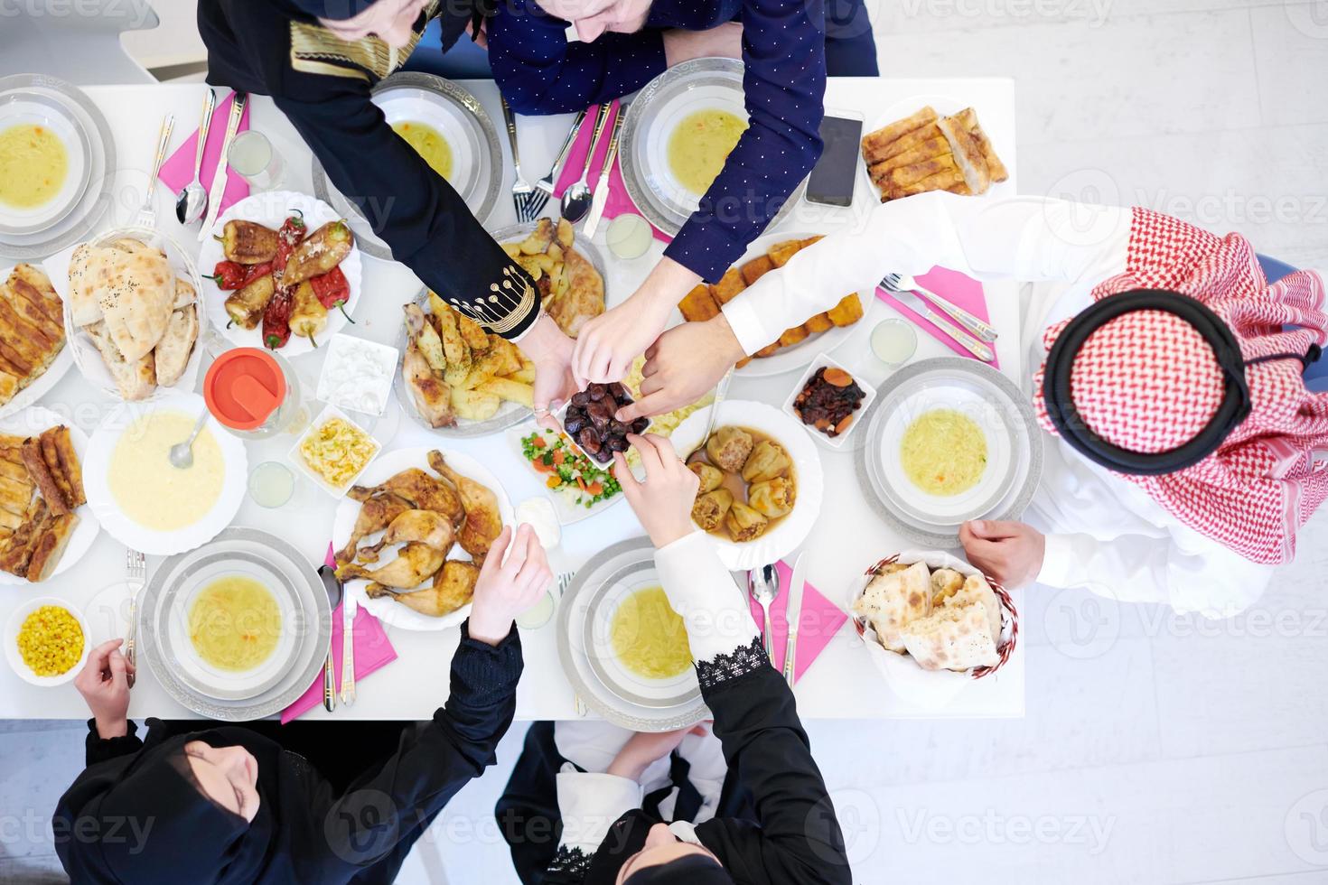 Muslim family having Iftar dinner eating dates to break feast top view photo