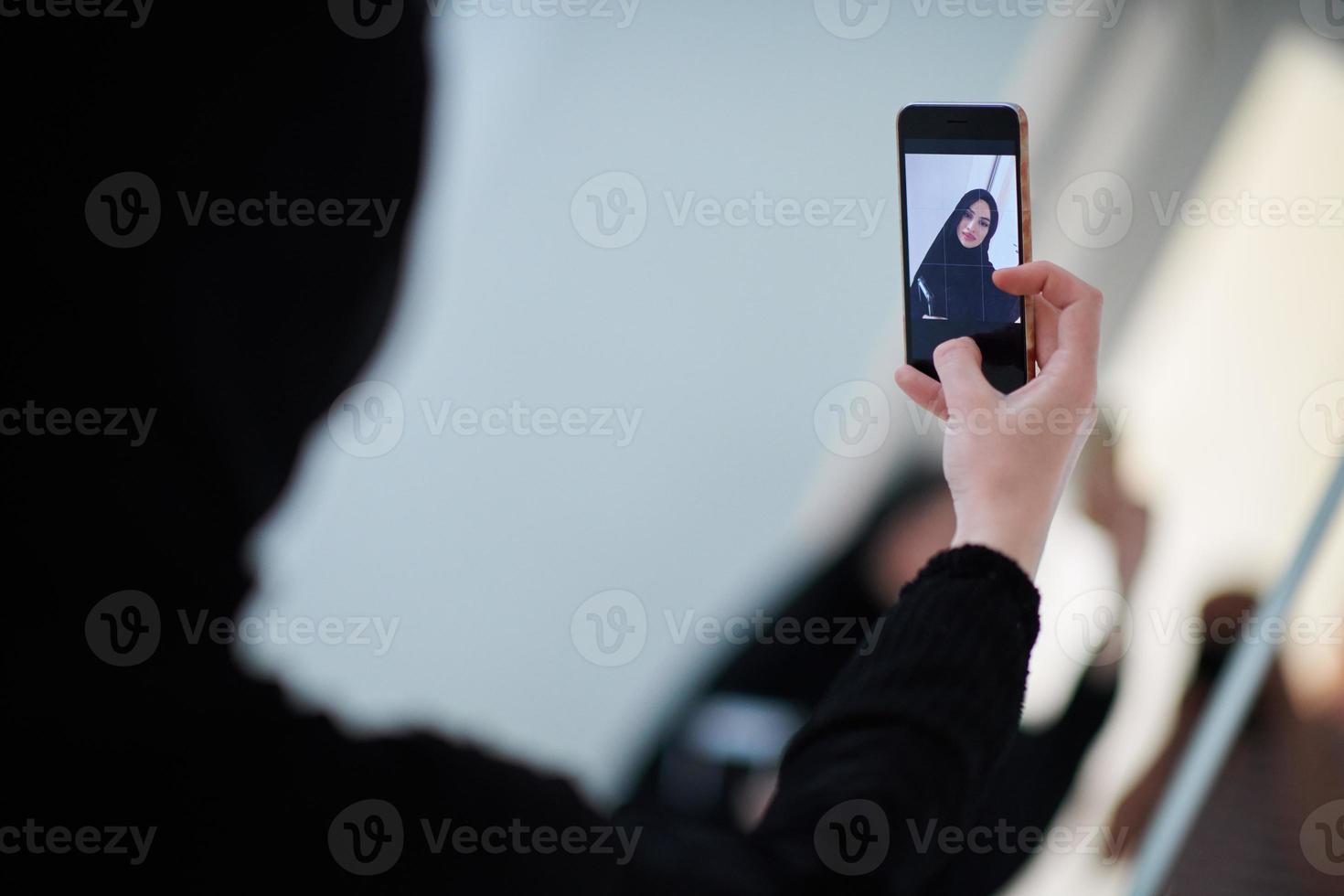 Young muslim businesswoman in traditional clothes or abaya taking selfie. photo