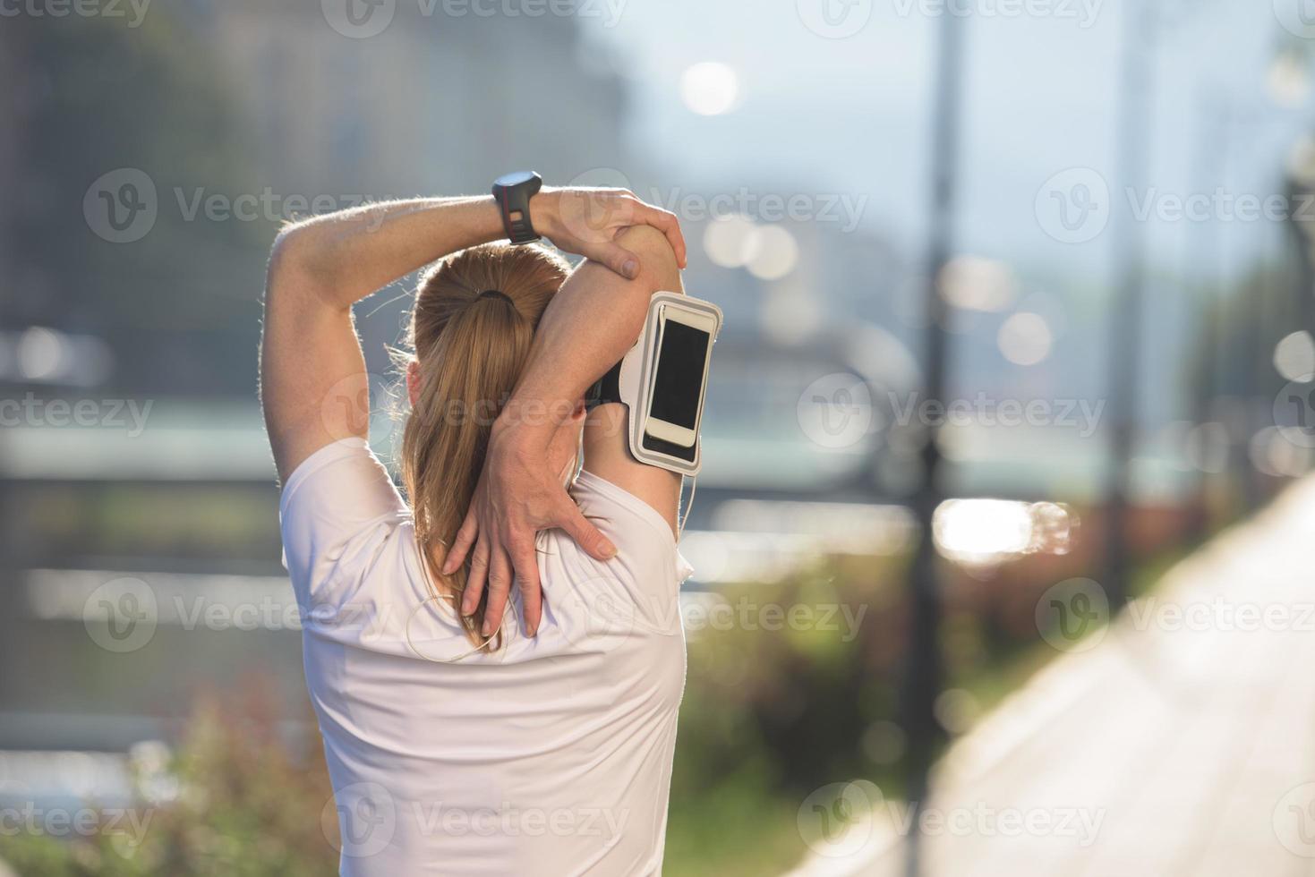 mujer rubia que se extiende antes de trotar por la mañana foto