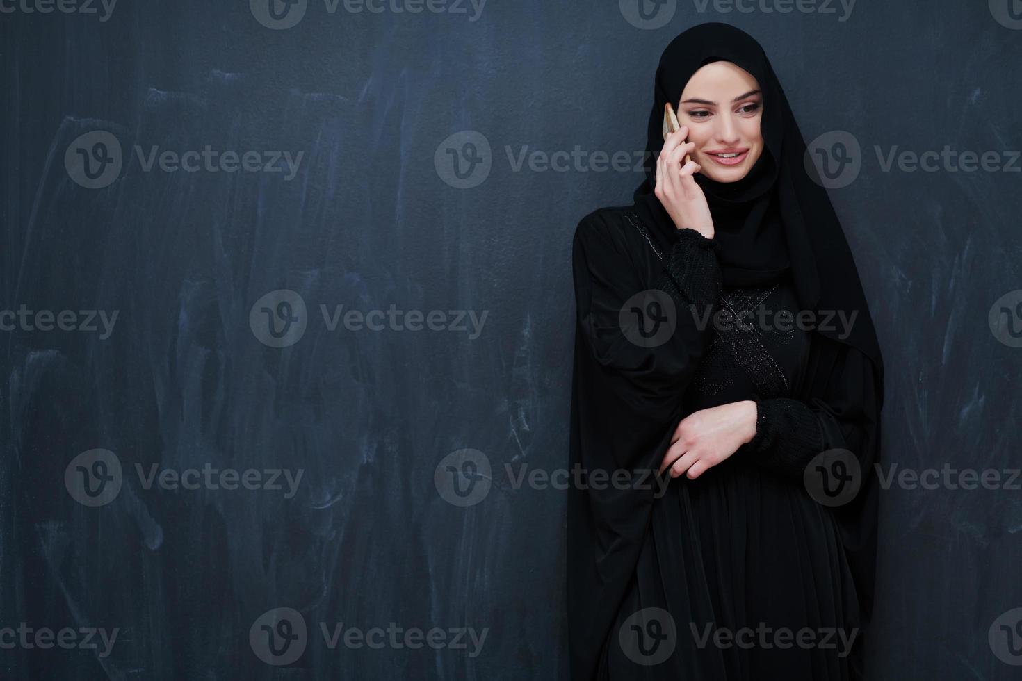 Young muslim businesswoman in traditional clothes or abaya using smartphone photo