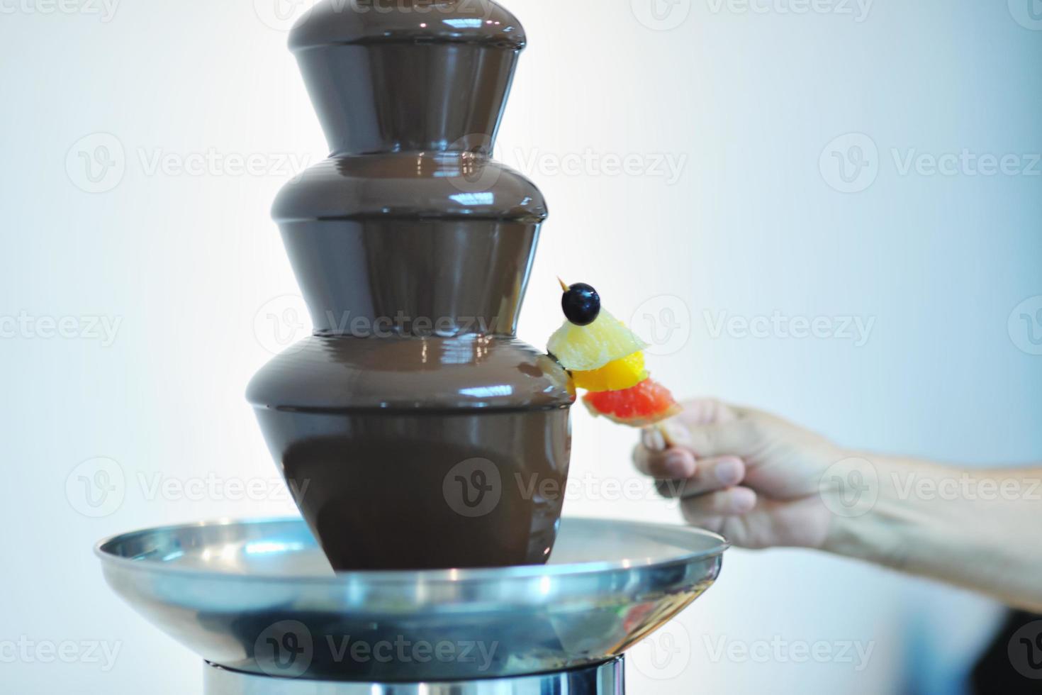 liquid chocolate fountain and fresh fruits on stick photo