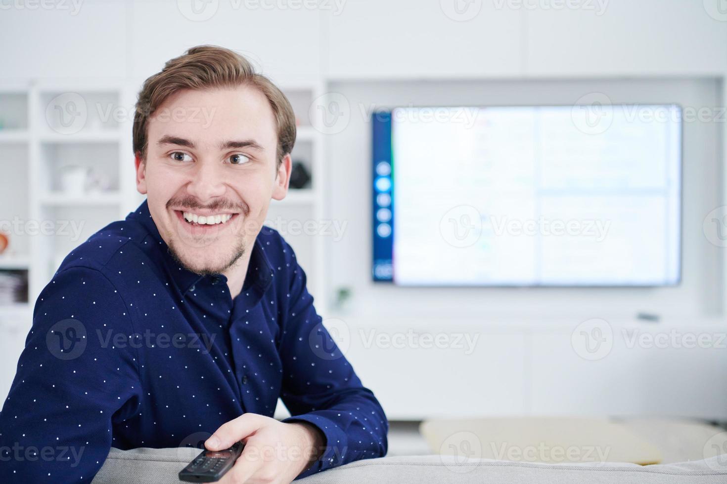 young man watching tv at big modern home photo