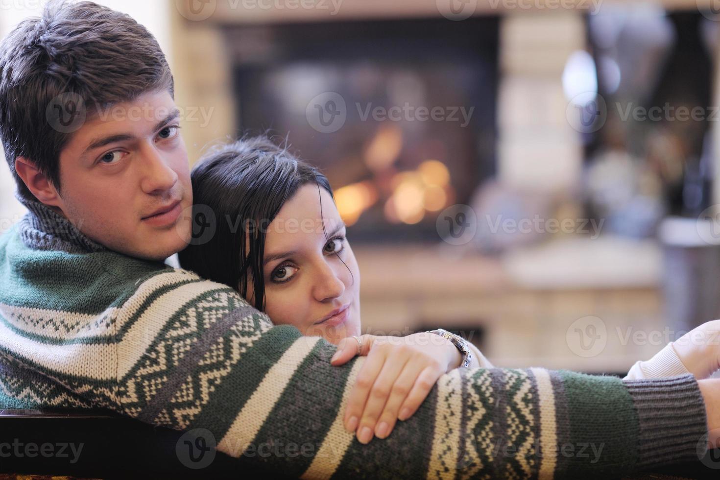 joven pareja romántica sentada y relajándose frente a la chimenea en casa foto