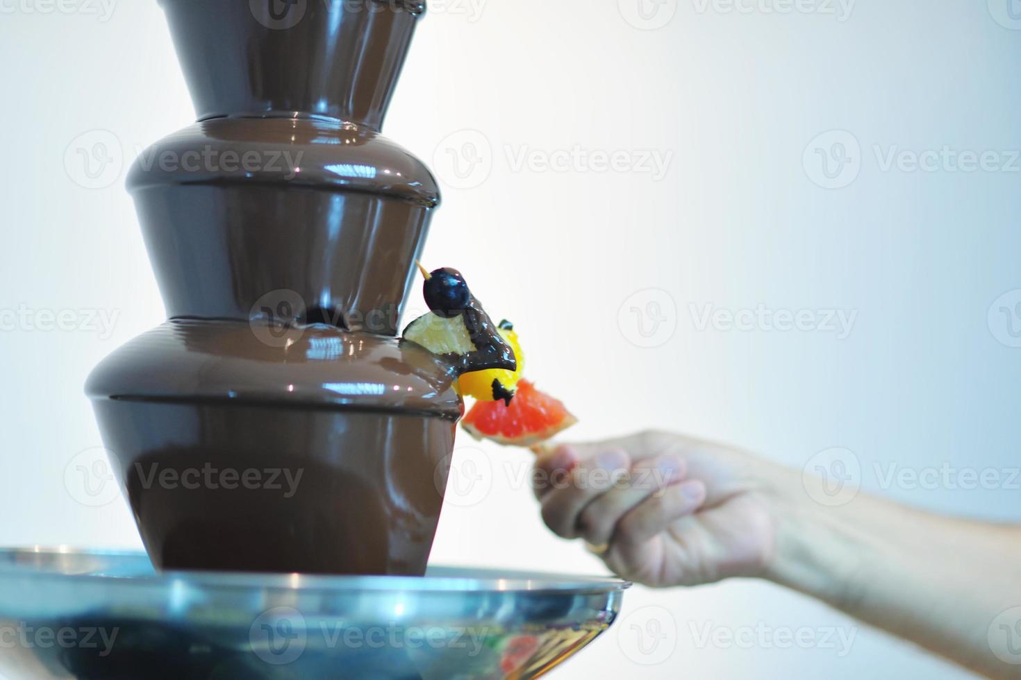liquid chocolate fountain and fresh fruits on stick photo
